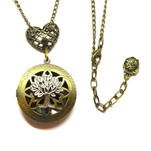 Könnte beinhalten: Eine goldfarbene Halskette mit einem Herzanhänger und einem runden Anhänger mit einem silbernen Lebensbaum-Design. Die Halskette hat einen Rosenanhänger an der Verlängerungskette.