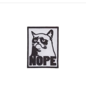May include: Black and white iron-on patch featuring a grumpy cat with the word "NOPE" underneath.