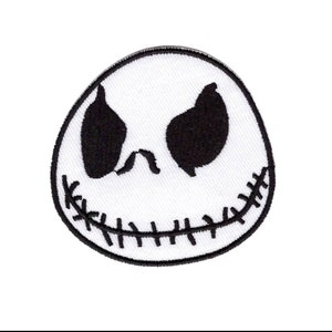 May include: Black and white embroidered patch of Jack Skellington's face from the Nightmare Before Christmas film. The patch features his signature stitched smile and one eye.