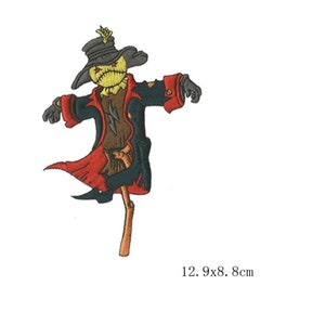 May include: A black and red embroidered scarecrow patch with a yellow face and a black hat. The patch is 12.9 x 8.8 cm.