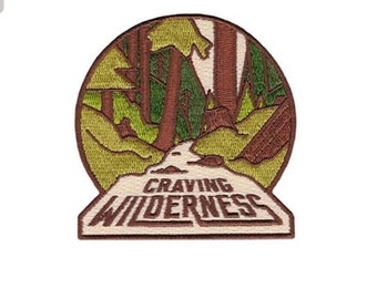 May include: Embroidered patch featuring a brown and green forest scene with the text "CRAVING WILDERNESS" in brown lettering.