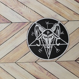 Può includere: Toppa ricamata in bianco e nero con un pentagramma e una testa di capra all'interno. La testa di capra ha le corna e un viso simile a un teschio.