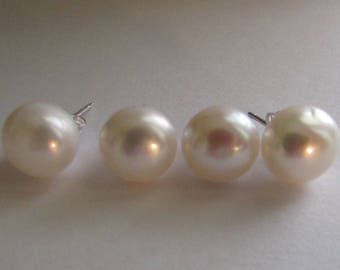 Puede incluir: Cuatro pendientes de perlas blancas con postes de plata. Las perlas tienen un brillo luminoso que refleja la luz. Los pendientes están dispuestos en fila sobre un fondo claro. Las perlas miden aproximadamente 1 cm de diámetro.