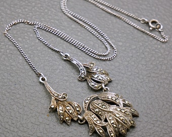 May include: A silver necklace with a pendant featuring a cluster of marcasite stones in a floral design.