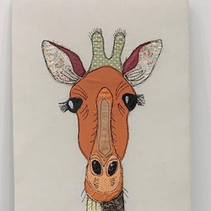 May include: A whimsical giraffe portrait on canvas. The giraffe's head is a warm orange hue, with detailed eyes and eyelashes. The neck is composed of colorful fabric squares, creating a patchwork effect. The background is a neutral off-white.