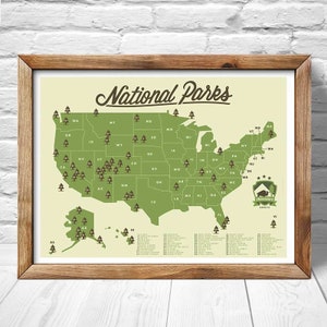 May include: A map of the United States with green pine tree icons marking the locations of all 63 National Parks. The map is framed in a brown wood frame. The text "National Parks" is written in a vintage style font at the top of the map. The text "Adventure Awaits" is written in a smaller font at the bottom of the map.