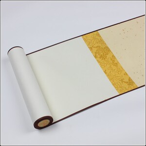 May include: A white scroll with a decorative border of gold and brown. The scroll is rolled up and tied with a brown ribbon.