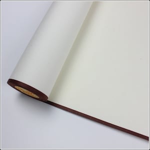 May include: A white scroll of paper with a brown border, rolled up and partially unfurled. The paper is smooth and has a slight texture.