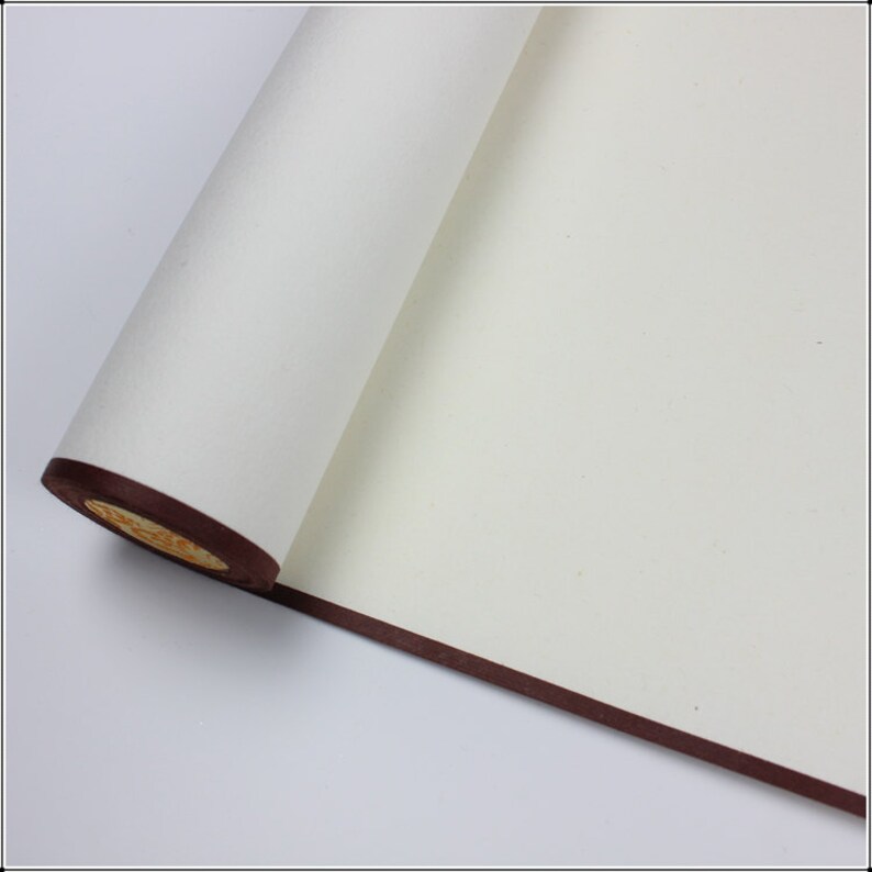 May include: A white scroll of paper with a brown border, rolled up and partially unfurled. The paper is smooth and has a slight texture.