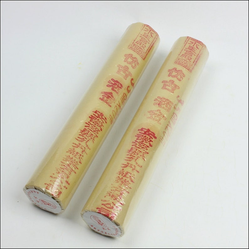 May include: Two rolls of yellow paper wrapped in clear plastic with red Chinese characters printed on the paper.