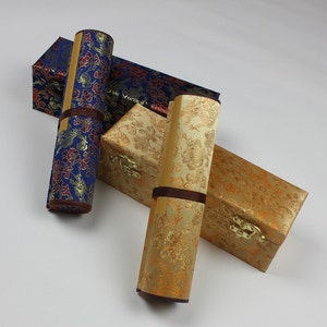 May include: Two rolled up scrolls with decorative fabric covers in gold and blue with floral patterns. The scrolls are in protective boxes with matching fabric covers.