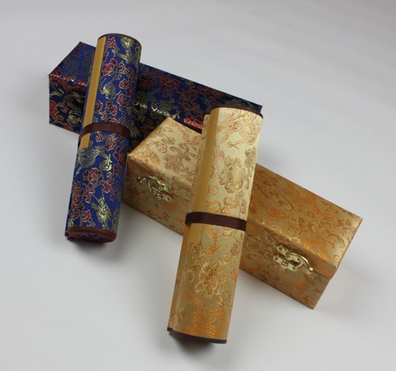 May include: Two rolled up scrolls with decorative fabric covers in gold and blue with floral patterns. The scrolls are in protective boxes with matching fabric covers.