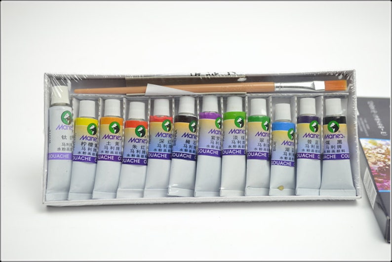 Puede incluir: Un juego de 12 pinturas de gouache en una caja de pl&aacute;stico con un pincel. Los tubos de pintura est&aacute;n etiquetados con "Mane" y tienen caracteres chinos. Los colores incluyen amarillo, naranja, rojo, marr&oacute;n, morado, verde, azul y negro.