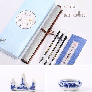 May include: A set of Chinese calligraphy supplies, including a scroll, three brushes, a brush holder, a blue and white porcelain inkwell, and a blue and white porcelain brush rest. The scroll is in a blue box with a white floral design. The brushes are in a clear plastic holder. The inkwell and brush rest are both decorated with a traditional Chinese design.