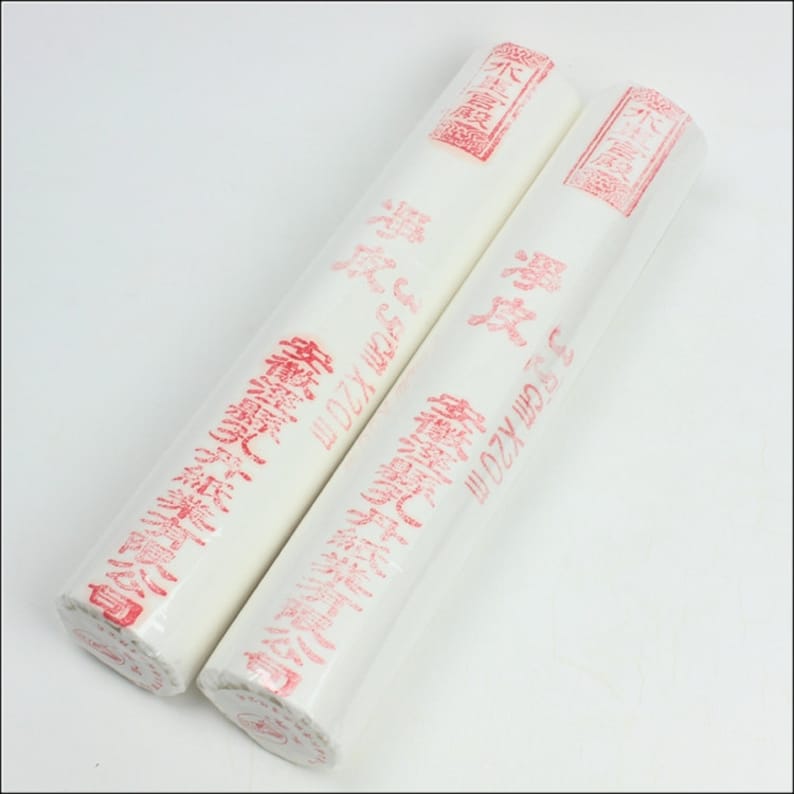 May include: Two rolls of white paper with red Chinese characters printed on them. The rolls are labeled with the text "33 cm X20 m" and "39 cm X20 m".