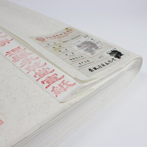 Pu&ograve; includere: Una pila di carta bianca con un timbro rosso e un'etichetta con testo cinese. L'etichetta include le parole "Numero dell'ispettore", "Data di produzione" e "安徽泾县太乾吃".