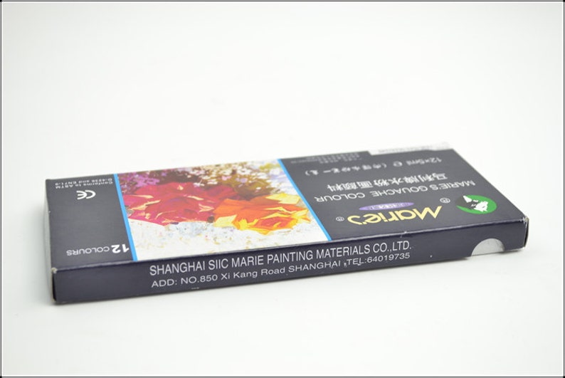 Puede incluir: Una caja azul de pintura gouache Marie's con una imagen floral en la parte delantera. La caja contiene 12 colores y est&aacute; fabricada por Shanghai Siic Marie Painting Materials Co., Ltd. El texto en la caja dice "Marie's Gouache Colour" y "12 Colours".