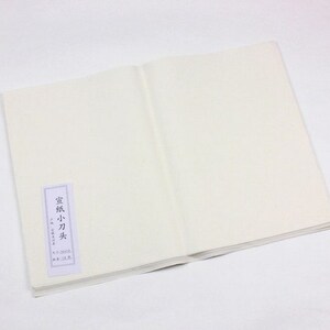 May include: A white, blank, paper notebook with a small, white label on the front cover. The label has Japanese text that reads "Washi 小刀尖".