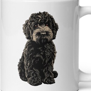 May include: White ceramic mug featuring a detailed illustration of a black dog with curly fur and a light brown muzzle. The dog is sitting, with its front paws together. The mug has a white handle and a glossy finish.