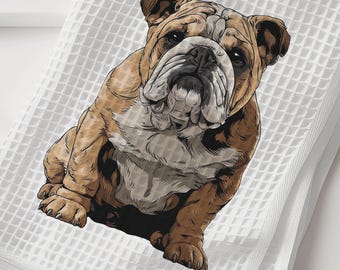 May include: White waffle-weave towel featuring a detailed illustration of a brown and white bulldog. The dog is sitting and facing forward. The towel is folded and placed on a white surface.