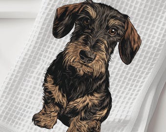 May include: A white waffle-weave kitchen towel featuring a detailed illustration of a wire-haired dachshund. The dog has black and tan fur, floppy ears, and a textured coat. The towel is folded and displays a clean, grid-like fabric pattern.