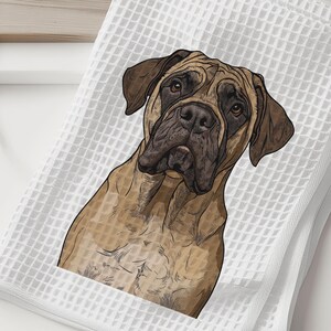 May include: White waffle-weave towel featuring a detailed illustration of a Mastiff dog. The dog is depicted in shades of brown and tan, with a focused expression. The towel is folded and appears clean and new.