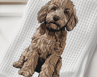 May include: White waffle-weave towel featuring a detailed illustration of a brown Goldendoodle dog. The dog is sitting upright with a focused expression. The towel is folded and placed on a white surface, suggesting a bathroom or kitchen setting.