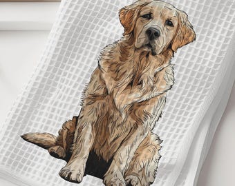 May include: White waffle-weave towel featuring a detailed illustration of a Golden Retriever dog. The dog is depicted in shades of brown and tan, sitting upright. The towel is folded and placed on a white surface, suggesting a bathroom or kitchen setting.