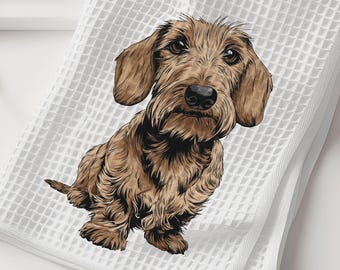 May include: A white waffle-weave kitchen towel featuring a detailed illustration of a brown wire-haired dachshund dog. The dog is depicted in a seated position with textured fur, floppy ears, and a black nose, centered on the fabric surface.