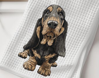 May include: A white waffle-weave kitchen towel featuring a detailed illustration of a black and tan Basset Hound. The dog is depicted in a seated position, showcasing its long ears, wrinkled face, and expressive eyes centered on the fabric.