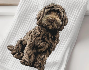 May include: White waffle-weave towel featuring a detailed illustration of a brown Labradoodle dog. The dog is depicted in a seated position with a fluffy coat. The towel is folded and placed on a white surface.