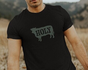 May include: A black t-shirt with a green silhouette of a cow and the word "HOLY" printed on the front.