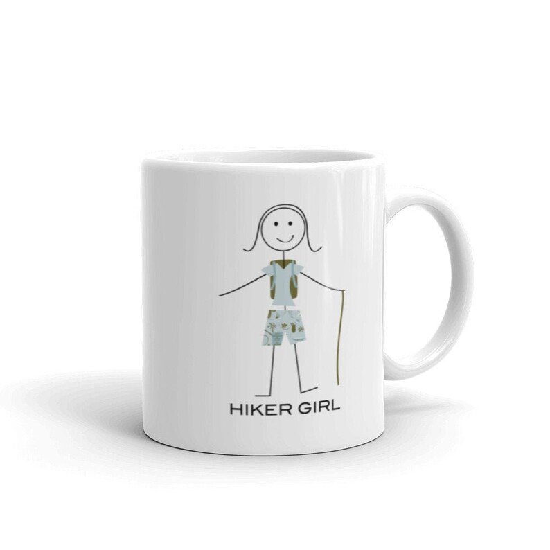 May include: White ceramic mug featuring a black stick figure illustration of a hiker girl wearing a backpack, shorts, and holding a walking stick. The text "HIKER GIRL" is printed below the illustration.
