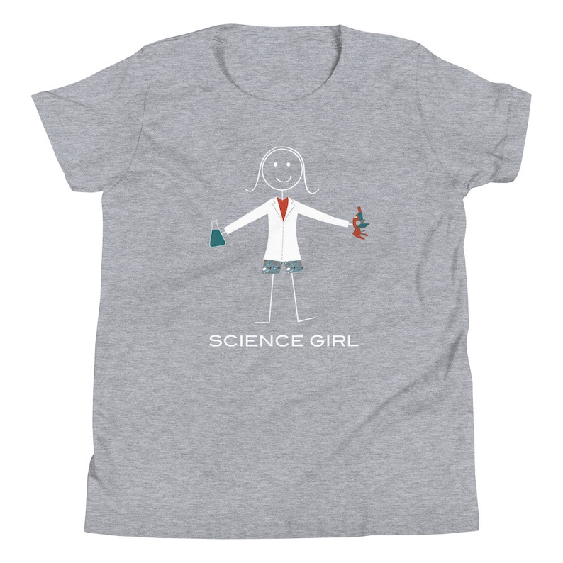 Puede incluir: Camiseta gris para j&oacute;venes con una ilustraci&oacute;n de un personaje de palo que lleva una bata de laboratorio blanca, sosteniendo un vaso de precipitados y un microscopio. El texto "SCIENCE GIRL" est&aacute; impreso debajo de la ilustraci&oacute;n.