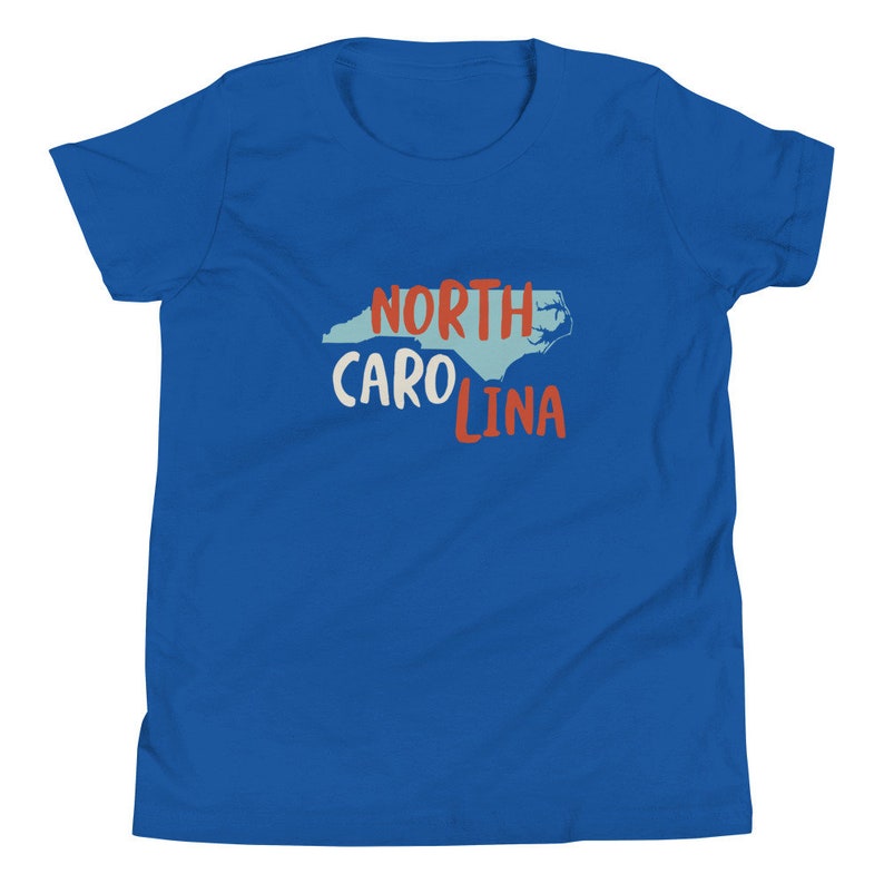 May include: A royal blue youth t-shirt with a white outline of the state of North Carolina and the text "NORTH CAROLINA" in red and white lettering.