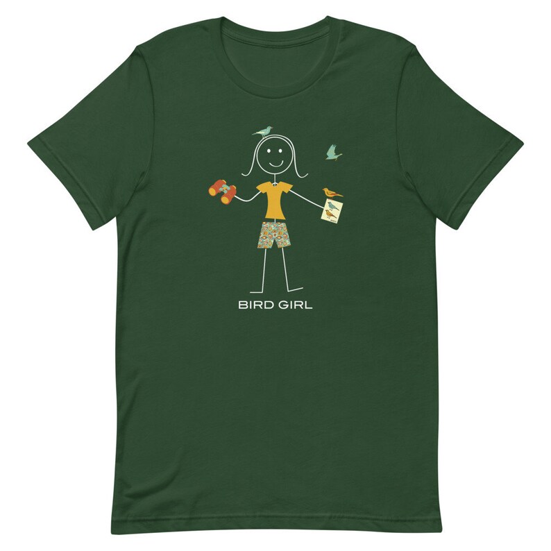 May include: A green t-shirt with a stick figure illustration of a person holding binoculars and a bird watching guide. The text "BIRD GIRL" is printed below the illustration.