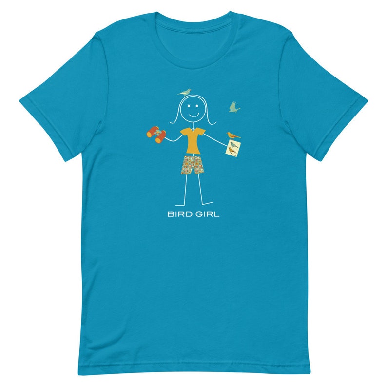 May include: A turquoise blue t-shirt with a stick figure illustration of a person holding binoculars and a bird watching guide. The text "BIRD GIRL" is printed below the illustration.