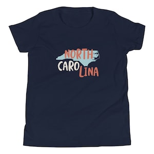 May include: A navy blue youth t-shirt with a light blue outline of the state of North Carolina and the text "NORTH CAROLINA" in red and white.