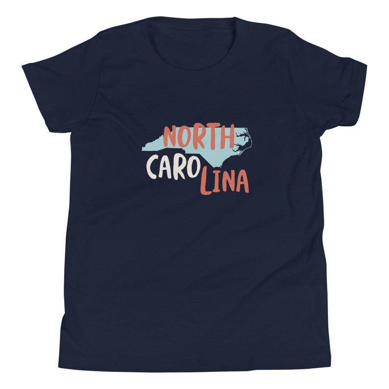 May include: A navy blue youth t-shirt with a light blue outline of the state of North Carolina and the text "NORTH CAROLINA" in red and white.
