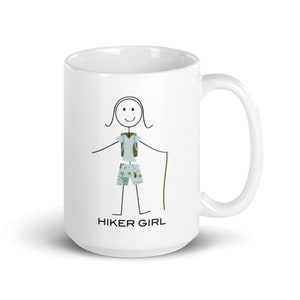 May include: White ceramic mug featuring a black stick figure illustration of a hiker wearing a blue shirt, green shorts, and a green backpack. The text "HIKER GIRL" is printed below the figure.