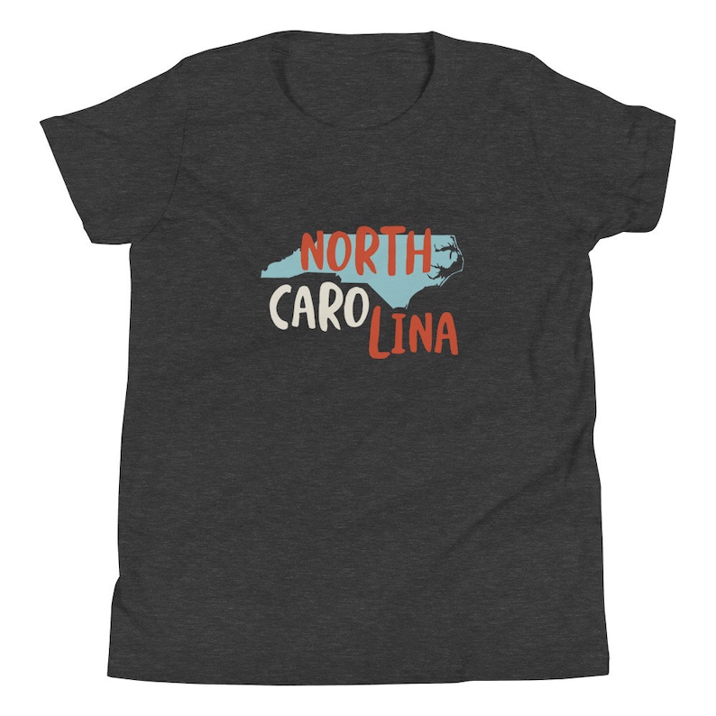 May include: A dark heather grey youth t-shirt with a blue outline of the state of North Carolina and the text "NORTH CAROLINA" in red and white lettering.