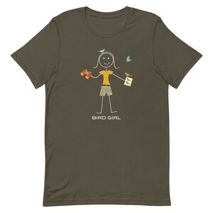 May include: A dark green t-shirt with a stick figure illustration of a person holding binoculars, a bird guide, and surrounded by birds. The text "BIRD GIRL" is printed below the illustration.