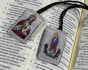 May include: Two religious-themed fabric patches with embroidered images. The first patch features a man with a beard and a halo, holding a book and a staff. The second patch features a woman in a blue robe with a crown and a halo, holding a baby. Both patches have a white background with gold accents.