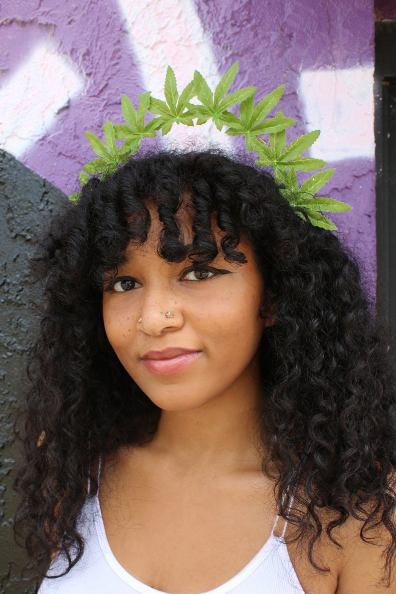 May include: A person with long, curly, black hair wearing a green leaf crown.