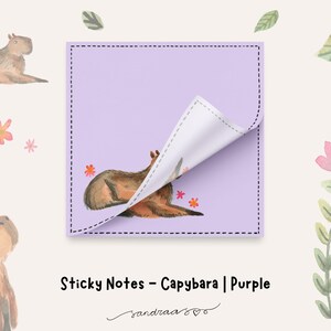May include: A lilac sticky note featuring a watercolour illustration of a capybara. The note has a corner peeled back, revealing the capybara illustration. The text "Sticky Notes - Capybara | Purple" is displayed below the note.