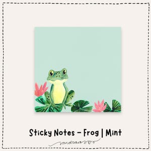 Op de afbeelding: Mintgroene zelfklevende notitieblaadjes met een groene kikkerillustratie met gele ogen, op waterlelies en roze bloemen. De tekst "Sticky Notes - Frog | Mint" staat eronder.