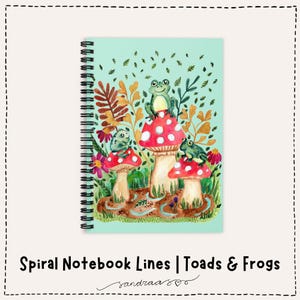 Peut inclure: Cahier à spirales avec une couverture bleu sarcelle clair représentant une illustration à l'aquarelle de trois grenouilles sur des chapeaux de champignons rouges et blancs. Le cahier porte le texte "Spiral Notebook Lines | Toads & Frogs".