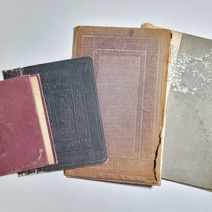 May include: A collection of four antique books featuring a small maroon volume, a dark blue book with embossed cover details, a large brown hardcover with intricate border patterns, and a grey book titled Havergal's Poems Complete.