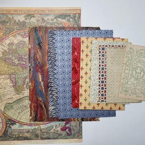May include: A collection of vintage paper ephemera, including a detailed antique map with colorful illustrations and text. Various patterned papers in red, blue, and cream tones are also visible, along with a decorative card.