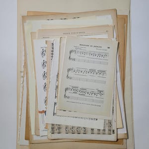 May include: A stack of vintage sheet music, including a page with the title "Berceuse de Jocelyn" and the composer "Rosina Gollan". The pages are yellowed with age and have a worn, antique look.